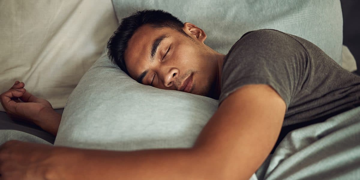 A young man sleeping soundly face-down on a pillow, representing rest in the days before the SAT.