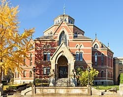 A Romanesque-style brick and stone academic building on Brown University’s Providence campus, framed by a golden autumn tree.