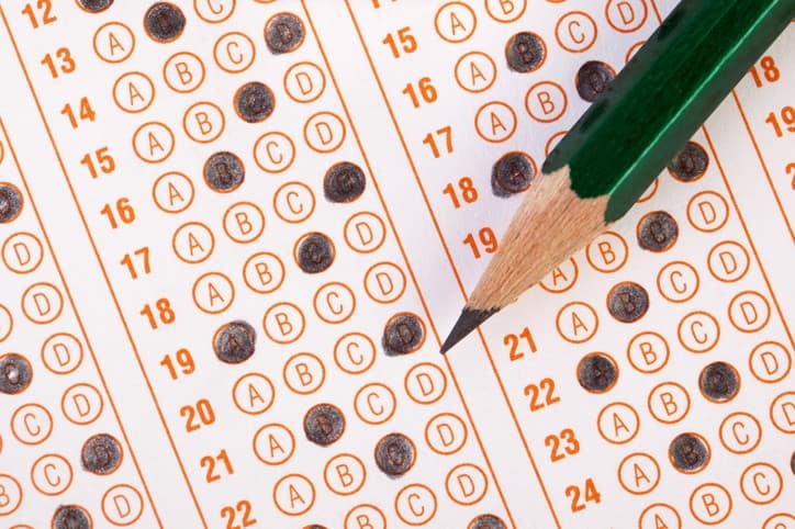 A close-up of a standardized test answer sheet with filled-in bubbles and a pencil resting across the rows.